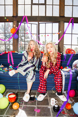 Courtney McBroom and Brie Larson sitting on a couch with party favors, balloons and streamers
